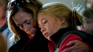 Molly Delaney, left, holds her 11-year-old daughter, Milly Delaney, during a service in honor of the victims who died a day earlier when a gunman opened fire at Sandy Hook Elementary School in Newtown, Conn., as people gathered at St. John's Episcopal Church in the Sandy Hook village of Newtown, Conn., Saturday, Dec. 15, 2012. (AP / Julio Cortez)