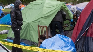 Police officers remove a brand new bike from a tent where a man was found dead at a tent city at Oppenheimer Park in the Downtown Eastside of Vancouver, on Wednesday, Oct. 15, 2014. (Darryl Dyck / THE CANADIAN PRESS)