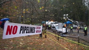 RCMP officers stand by on Burnaby Mountain as Kinder Morgan contractors prepare to drill a borehole in preparation for the Trans Mountain Pipeline expansion in Burnaby, B.C., on Friday November 21, 2014. (THE CANADIAN PRESS/Darryl Dyck)