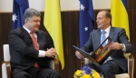 Australian Prime Minister Tony Abbott, right, holds a book given to him by Ukrainian President Petro Poroshenko as they meet at the federal government office in Melbourne, Australia on Thursday, Dec. 11, 2014. (AP / Julian Smith) 