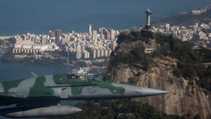 A F-5 fighter flies past the Christ the Redeemer statue while intercepting another aircraft, photographed through a window, during a Brazilian Air Force presentation for the press ahead of the Olympic games in Rio de Janeiro, Brazil, Thursday, July 14, 2016. (Felipe Dana/AP Photo)