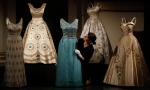 A woman adjusts evening dresses of Britain's Queen Elizabeth at an exhibition at Buckingham Palace in London, Thursday, July 21, 2016. (AP Photo/Frank Augstein)