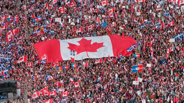 A large Canadian flag is passed through a crowd