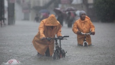 Two men push their bikes along a flooded area in Rizal, east of Manila, Philippines on Tuesday Aug. 7, 2012. (AP / John Javellana)