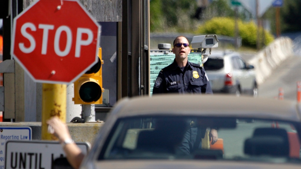 A U.S. Customs and Border Protection officer looks toward a car coming toward him in this 2009 file photo. (AP / Elaine Thompson)