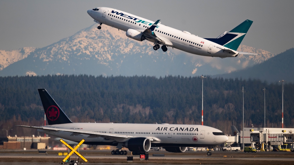 An Air Canada flight departing for Toronto, bottom, taxis to a runway as a Westjet flight bound for Palm Springs takes off at Vancouver International Airport, in Richmond, B.C., Friday, March 20, 2020. THE CANADIAN PRESS/Darryl Dyck