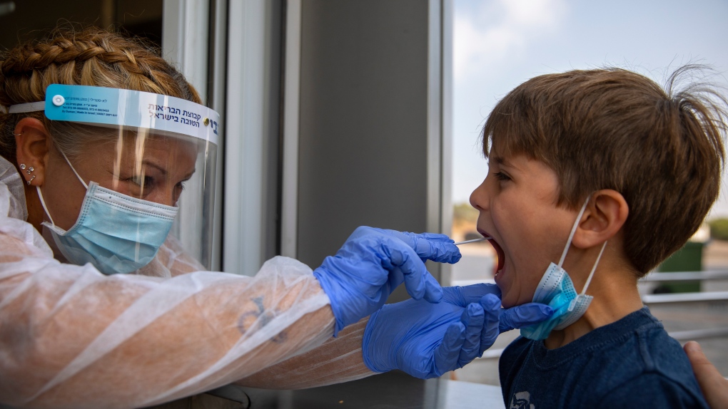A health worker collects a swab sample from a kid to test for COVID-19, at a coronavirus testing center, in Tel Aviv, Israel, Monday, Aug. 9, 2021. (AP Photo/Oded Balilty)