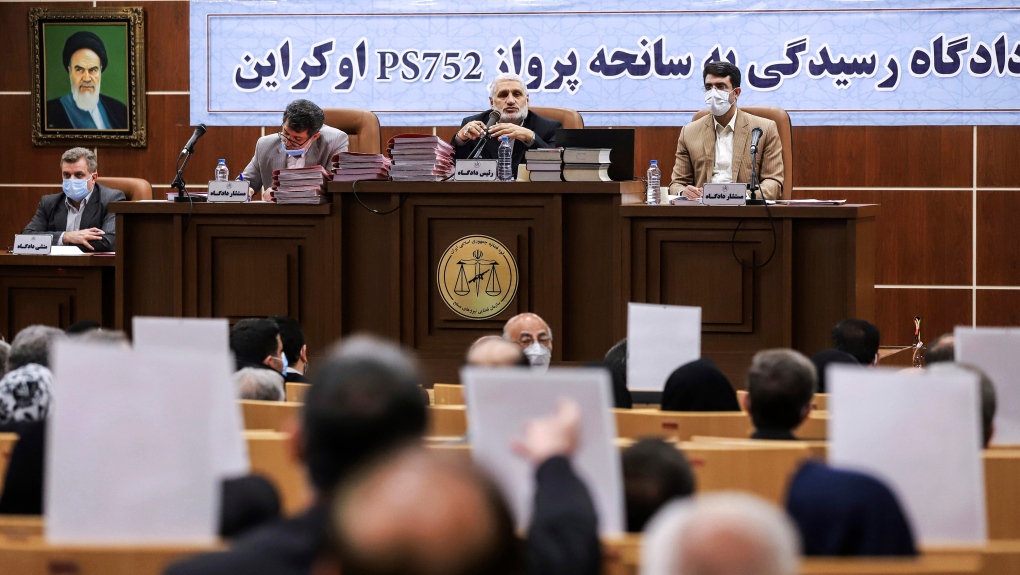 This photo released by Mizan News Agency, shows a hearing in an Iranian military courtroom for the 2020 downing of a Ukrainian plane that killed 176 people, Sunday, Nov. 21, 2021, in Tehran, Iran. The banner at rear next to the portrait of the late Iranian revolutionary founder Ayatollah Khomeini reads in Persian: "The trial of Ukrainian flight PS752 accident." (Koosha Mahshid Falahi/Mizan News Agency via AP) 