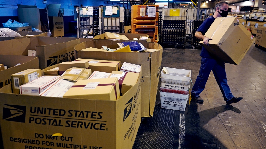 A worker carries a large parcel at the United States Postal Service sorting and processing facility, Thursday, Nov. 18, 2021, in Boston. Last year's holiday season was far from the most wonderful time of the year for the beleaguered U.S. Postal Service. Shippers are now gearing up for another holiday crush.(AP Photo/Charles Krupa) 
