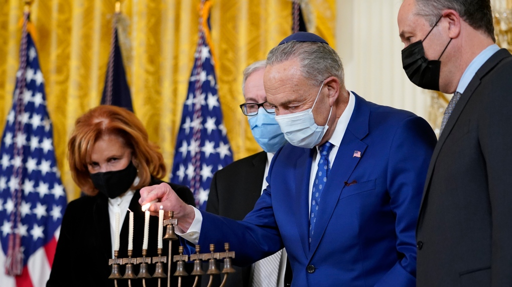 U.S. Senate Majority Leader Chuck Schumer of N.Y., second from right, lights the menorah in the East Room of the White House in Washington, during an event to celebrate Hanukkah, Wednesday, Dec. 1, 2021. (AP Photo/Susan Walsh) 
