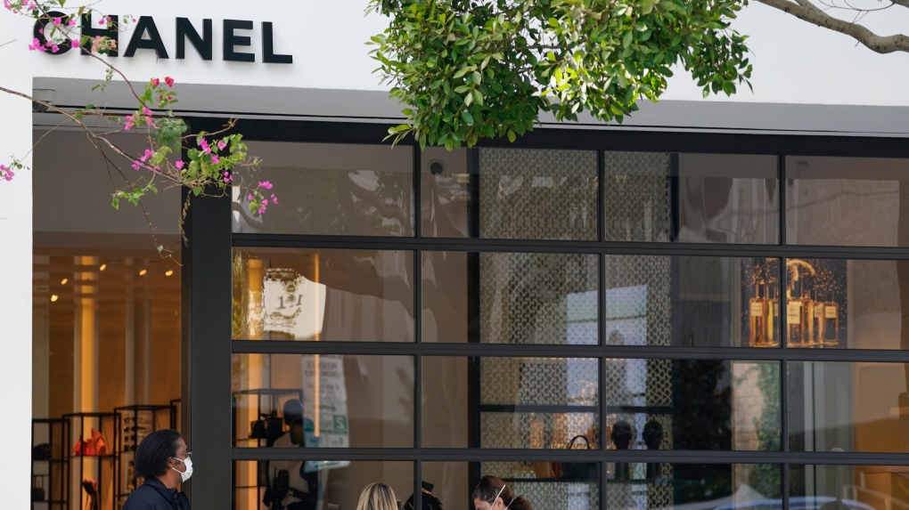 Customers wearing masks wait to enter a Chanel store Wednesday, Nov. 18, 2020, in the West Hollywood area of Los Angeles. (AP Photo/Ashley Landis) 