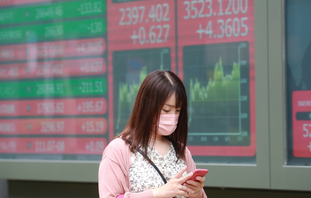 A woman walks by an electronic stock board of a securities firm in Tokyo, Monday, July 5, 2021. (AP Photo/Koji Sasahara) 