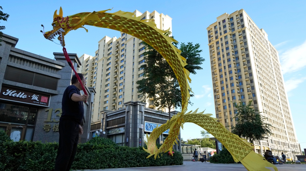 A resident wields a cloth dragon outside the Evergrande Yujing Bay residential complex in Beijing, China, Tuesday, Sept. 21, 2021. (AP Photo/Ng Han Guan) 