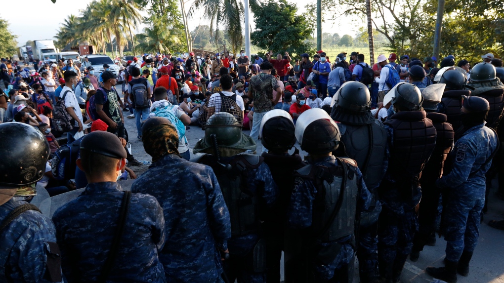 Guatemala's military stops migrants who are part of a caravan from Honduras hoping to reach the United States after they crossed the border in Puerto Barrios, Guatemala, Saturday, Jan. 15, 2022. (AP Photo/Delmer Martinez) 