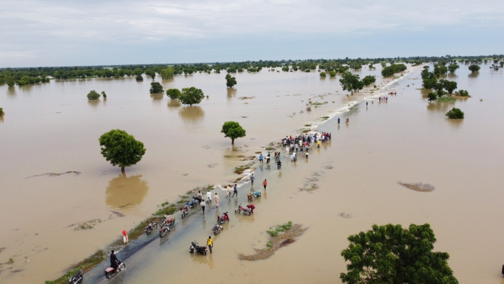 People walk through floodwaters after heavy rainfall in Hadeja, Nigeria, Sept 19, 2022. (AP Photo)