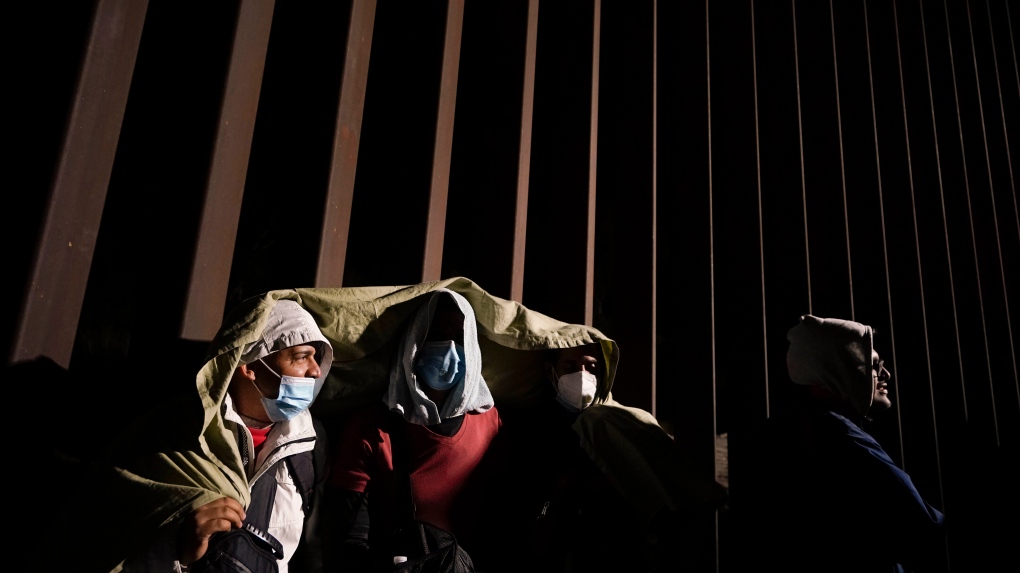 FILE - Four men from Cuba try to keep warm after crossing the border from Mexico and surrendering to authorities to apply for asylum on Nov. 3, 2022, near Yuma, Ariz. U.S. District Judge Emmet Sullivan on Tuesday, Nov. 15, ordered the Biden administration to lift Trump-era asylum restrictions that have been a cornerstone of border enforcement since the beginning of COVID-19. Sullivan ruled that Title 42 authority end immediately for families and single adults, saying it violates federal rule-making procedures. (AP Photo/Gregory Bull, File)