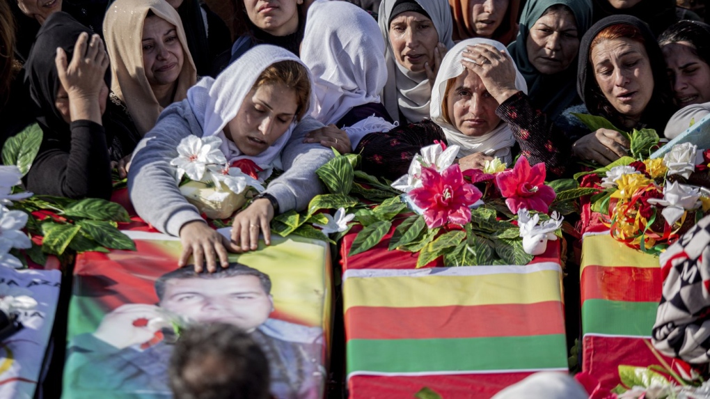 Syrian Kurds attend a funeral of people killed in Turkish airstrikes in the village of Al Malikiyah , northern Syria, Monday, Nov. 21, 2022. (AP Photo/Baderkhan Ahmad)