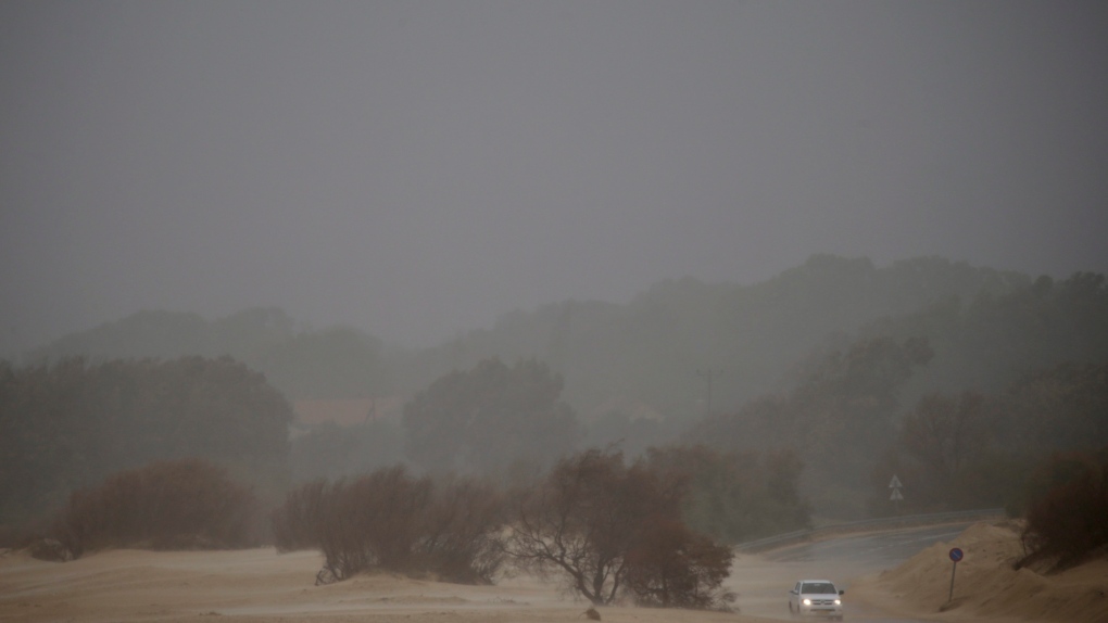 A car drives through rain, wind and sand in Michmoret, Israel, Wednesday, Jan. 16, 2019. (AP Photo/Ariel Schalit)
