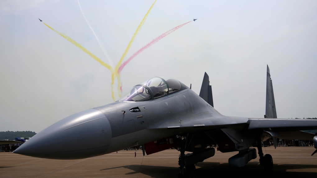 Members of the 'August 1st' Aerobatic Team of the Chinese People's Liberation Army (PLA) Air Force perform near a J-16D electronic warfare airplane during the 13th China International Aviation and Aerospace Exhibition, also known as Airshow China 2021, on Wednesday, Sept. 29, 2021 in Zhuhai in southern China's Guangdong province. (AP Photo/Ng Han Guan)