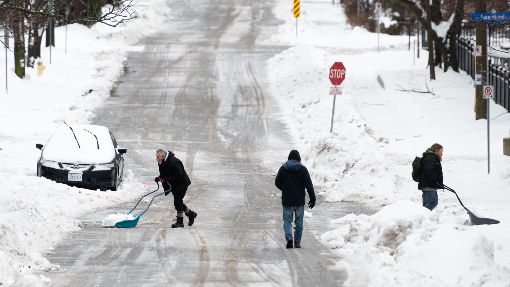 People shovel snow in the Sandy Hill neighbourhood of Ottawa, on Friday, Dec. 23, 2022. Environment Canada has issued a winter storm warning for the region which is calling for flash freezing, icy and slippery surfaces, wind gusts and chills. THE CANADIAN PRESS/Spencer Colby