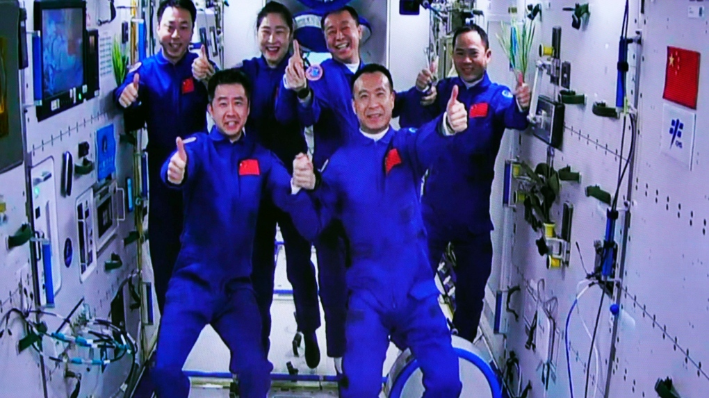 In this photo released by Xinhua News Agency, an image captured off a screen at the Jiuquan Satellite Launch Center in northwest China shows the Shenzhou-15 and Shenzhou-14 crew taking a group picture with their thumbs up after a historic gathering in space on Wednesday, Nov. 30, 2022. Three Chinese astronauts docked early Wednesday with their country's space station, where they will overlap for several days with the three-member crew already onboard and expand the facility to its maximum size. (Guo Zhongzheng/Xinhua via AP)