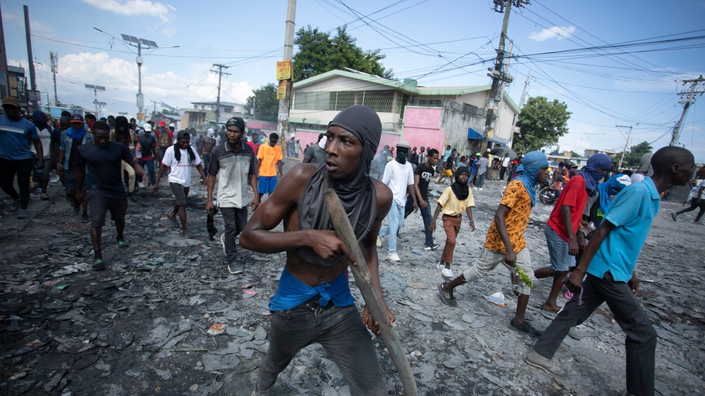 A protester carries a piece of wood simulating a weapon during a protest demanding the resignation of Prime Minister Ariel Henry in the Petion-Ville area of Port-au-Prince, Haiti, on Oct. 3, 2022. (AP Photo/Odelyn Joseph)
