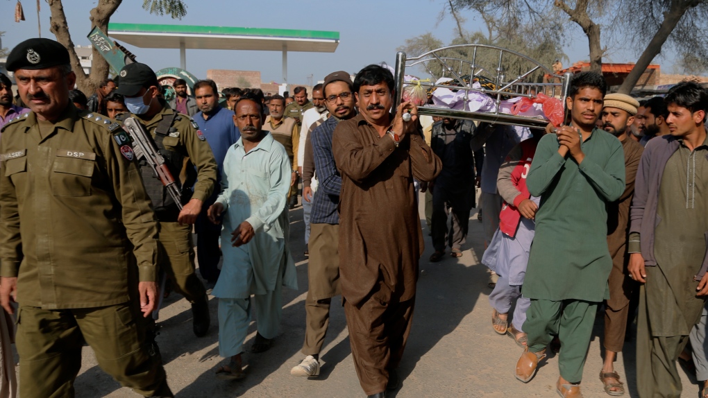 Police officers escort relatives carrying the body of Mushtaq Ahmed, 41, who was killed when an enraged mob stoned him to death for allegedly desecrating the Quran, in eastern Pakistan, Sunday, Feb. 13, 2022.  (AP Photo/Asim Tanveer)