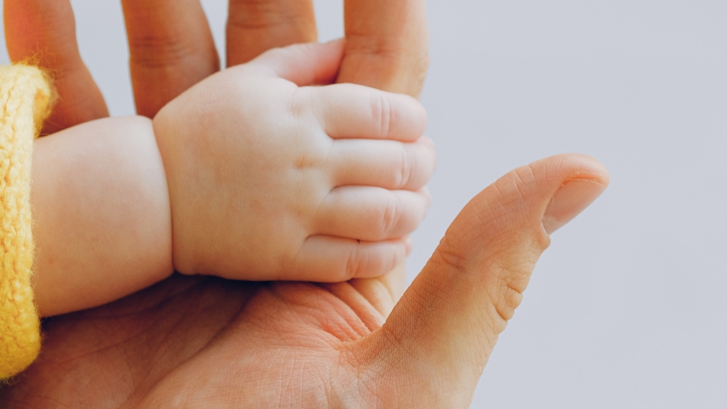 A person holds a baby's hand. (Pexels.com)