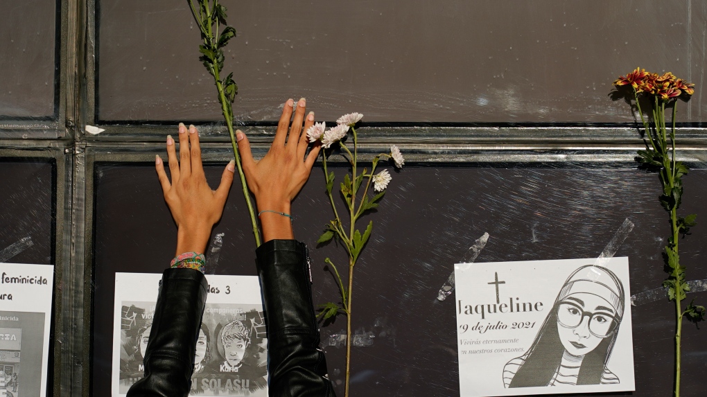 A woman places a stem of flowers on the facade of the Attorney General's office during a protest against the disappearance of Debanhi Escobar and other women who have gone missing, in Mexico City, Friday, April 22, 2022. (AP Photo/Eduardo Verdugo)