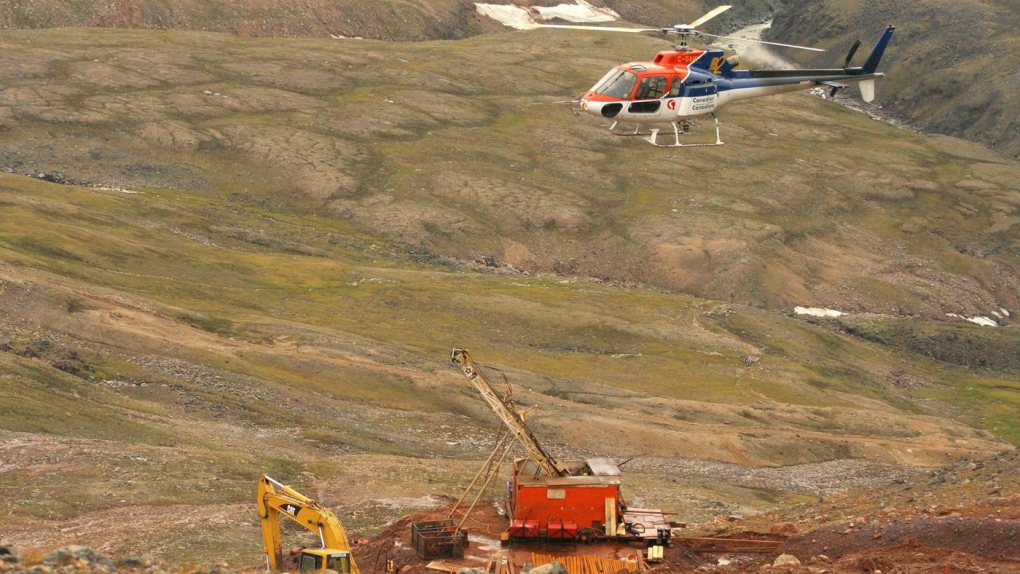 A helicopter passes over excavation equipment at the Mary River exploration camp, the site of a proposed iron mine on northern Baffin Island, in this Aug. 17, 2006, file photo. THE CANADIAN PRESS/Vinne Karetak