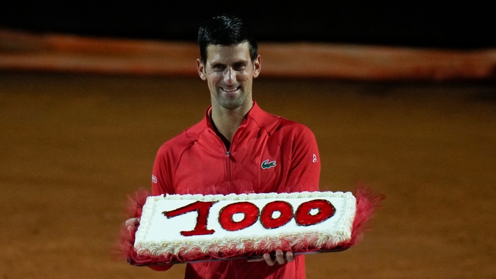 Serbia's Novak Djokovic holds a cake adorned with the number of his 1,000th tour-level win earned after winning his semifinal match against Norway's Casper Ruud at the Italian Open tennis tournament, in Rome, May 14, 2022. (AP Photo/Alessandra Tarantino)