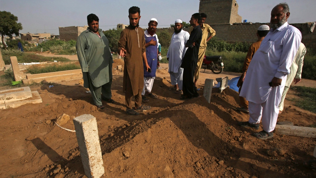 FILE - People look at the graves of alleged victims of two so-called honour killings, in Karachi, Pakistan, Wednesday, Sept. 13, 2017. (AP Photo/Fareed Khan)