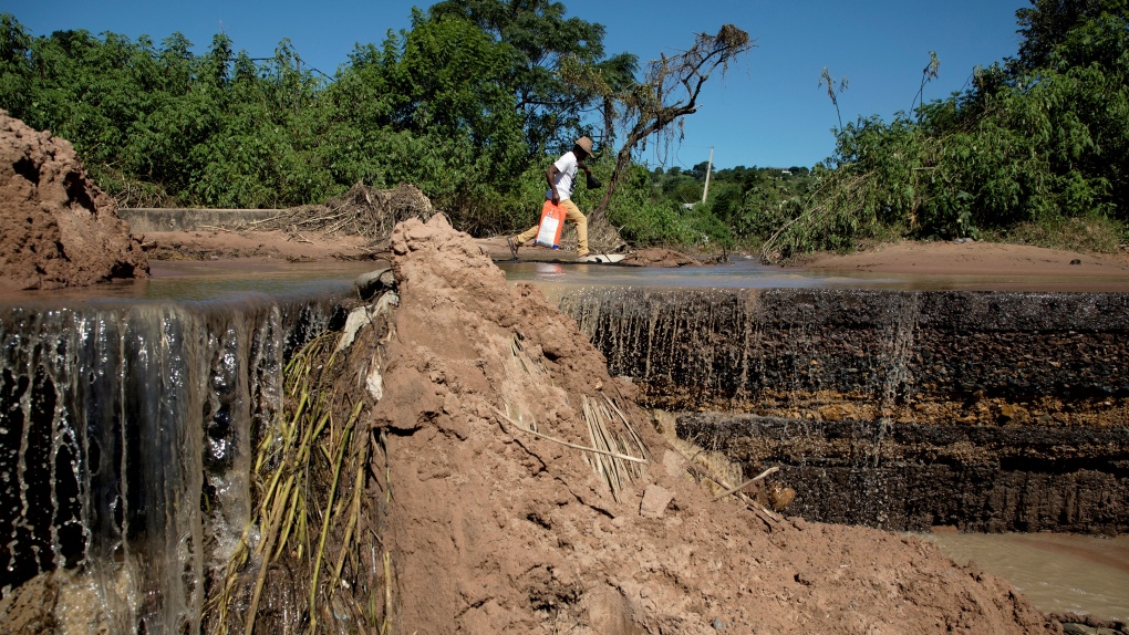 A man jumps past a sewer as he crosses a damaged road in Pinetown, near Durban, South Africa, Wednesday, April 20, 2022. (AP Photo/Str)