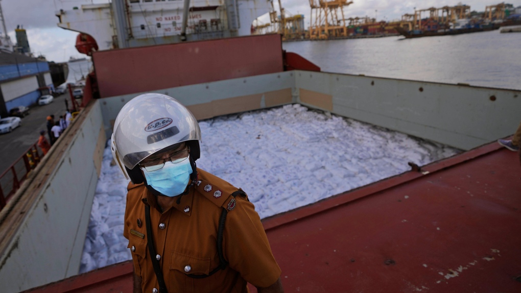A Sri Lankan port worker stands on a ship that carried emergency supplies granted as humanitarian aid by India government to Sri Lankan people at a port in Colombo, Sri Lanka, Sunday, May 22, 2022. (AP Photo/Eranga Jayawardena)