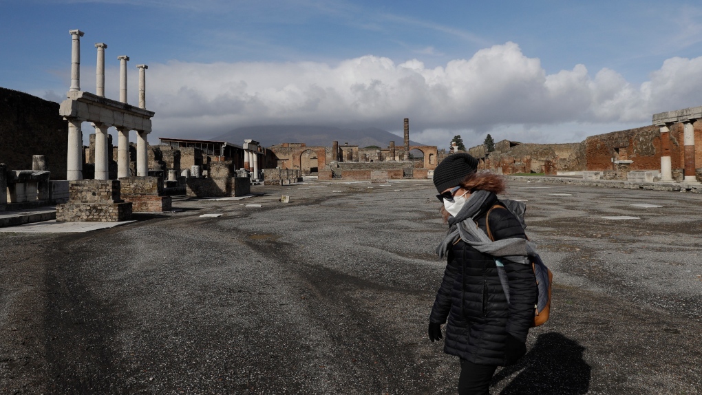 Clouds hang over the Vesuvius volcano, background, as a woman walks in the Forum of the archeological site of Pompeii, southern Italy, during the inauguration of the museum Antiquarium, Monday, Jan. 25, 2021. (AP Photo/Gregorio Borgia)