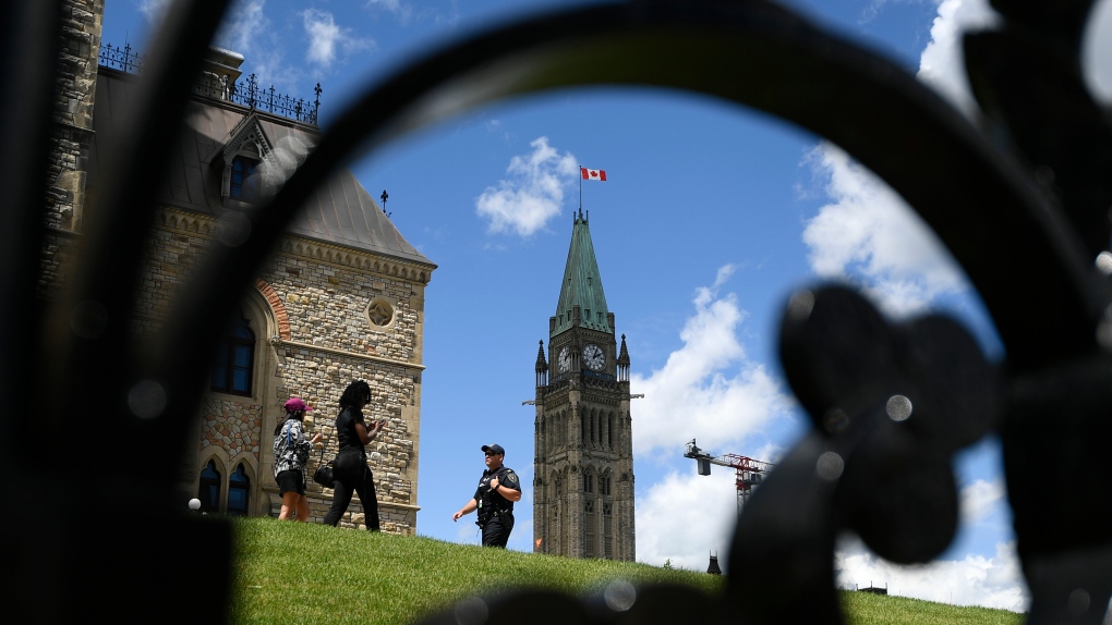 Centre Block’s Peace Tower is seen behind as a Parliamentary Protective Services officer walks on Parliament Hill in Ottawa, on Friday, June 17, 2022. THE CANADIAN PRESS/Justin Tang