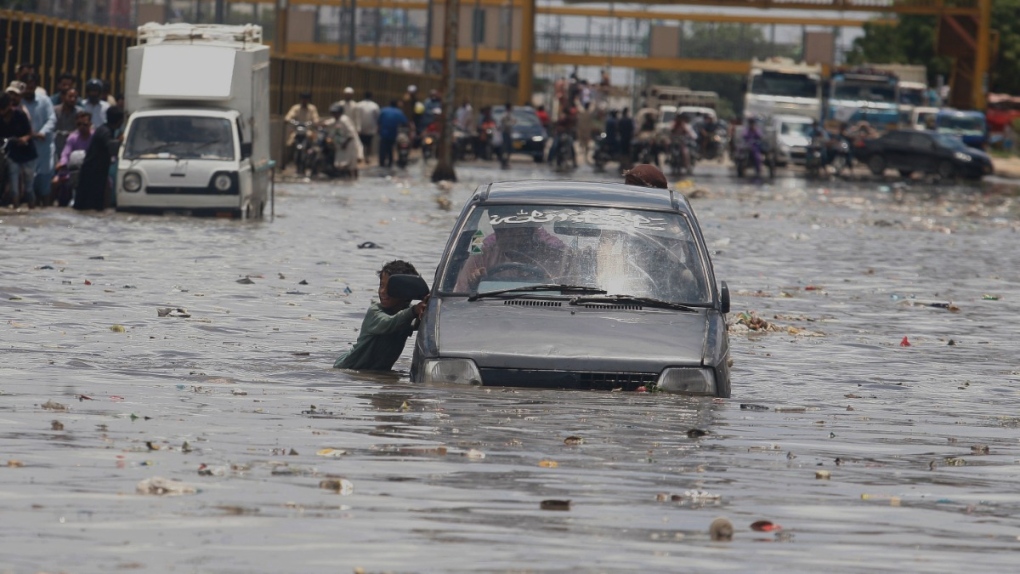 A car drives on a flooded road after a heavy rainfall in Karachi, Pakistan, on July 11, 2022. (Fareed Khan / AP) 