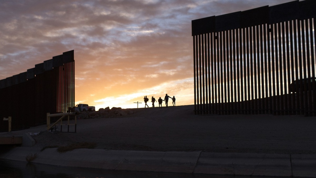Migrant families from Brazil pass through a gap in the border wall to reach the United States after crossing from Mexico in Yuma, Ariz., on June 10, 2021. (Eugene Garcia / AP) 