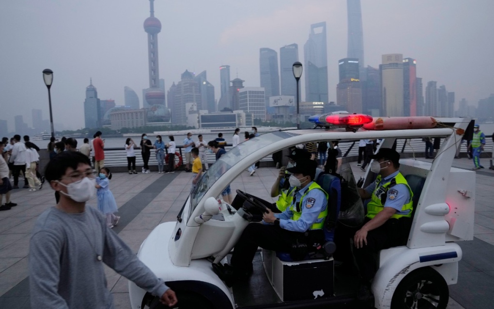 A police patrol vehicle monitors the crowd along the bund, June 1, 2022, in Shanghai. (AP Photo/Ng Han Guan)
