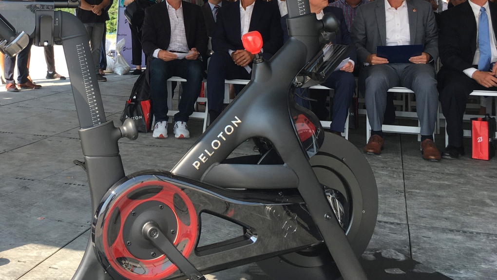 Peloton CEO John Foley, left, is seen behind one of his company's fitness machine along with others gathered for the groundbreaking for the company's first U.S. factory, Monday, Aug. 9, 2021, in Luckey, Ohio. (AP Photo/John Seewer)
