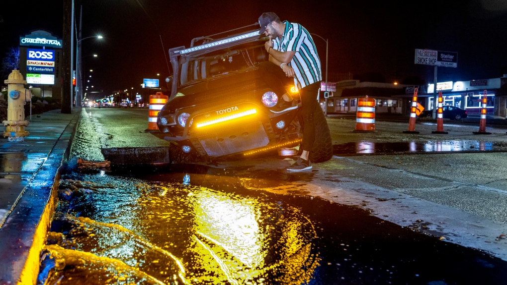 Driver Miguel Reyes checks out his vehicle stuck in a construction hole due to flooding along Charleston Blvd. adjacent to Tacos El Gordon as a powerful storm moves through the area on Thursday, July 28, 2022, in Las Vegas. (L.E. Baskow/Las Vegas Review-Journal via AP)