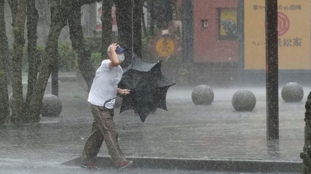 A man is drenched by the rain brought by Tropical Storm Meari, in Hamamatsu, Shizuoka prefecture, central Japan Saturday, Aug. 13, 2022. (Kyodo News via AP)