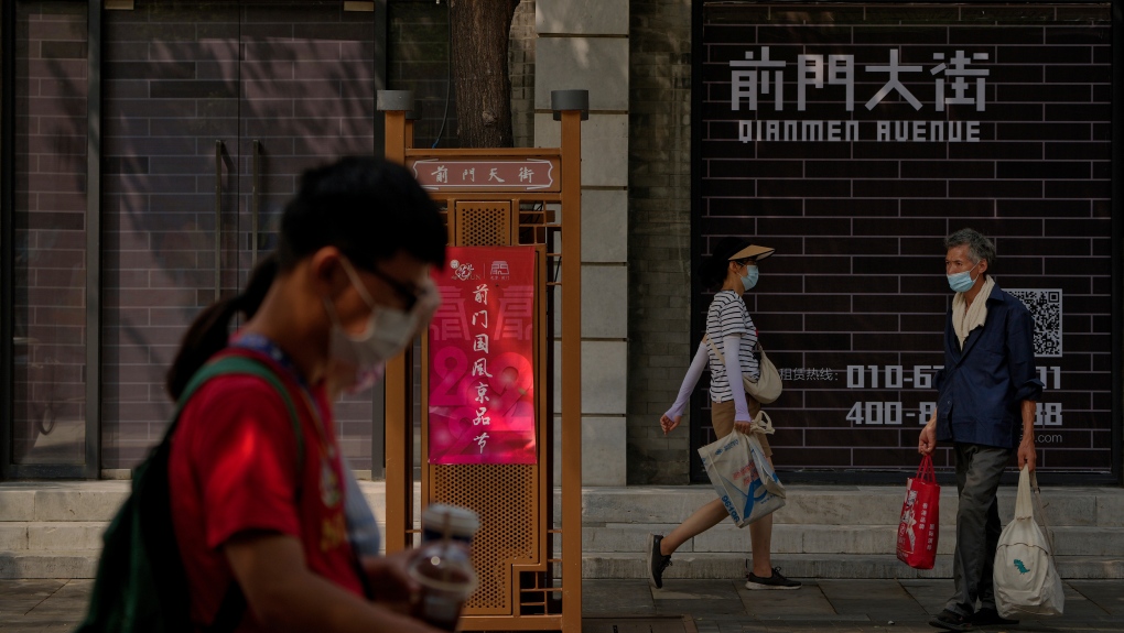 Visitors wearing face masks tour past vacant shop lots at Qianmen Street in Beijing, Wednesday, Aug. 17, 2022. (AP Photo/Andy Wong)