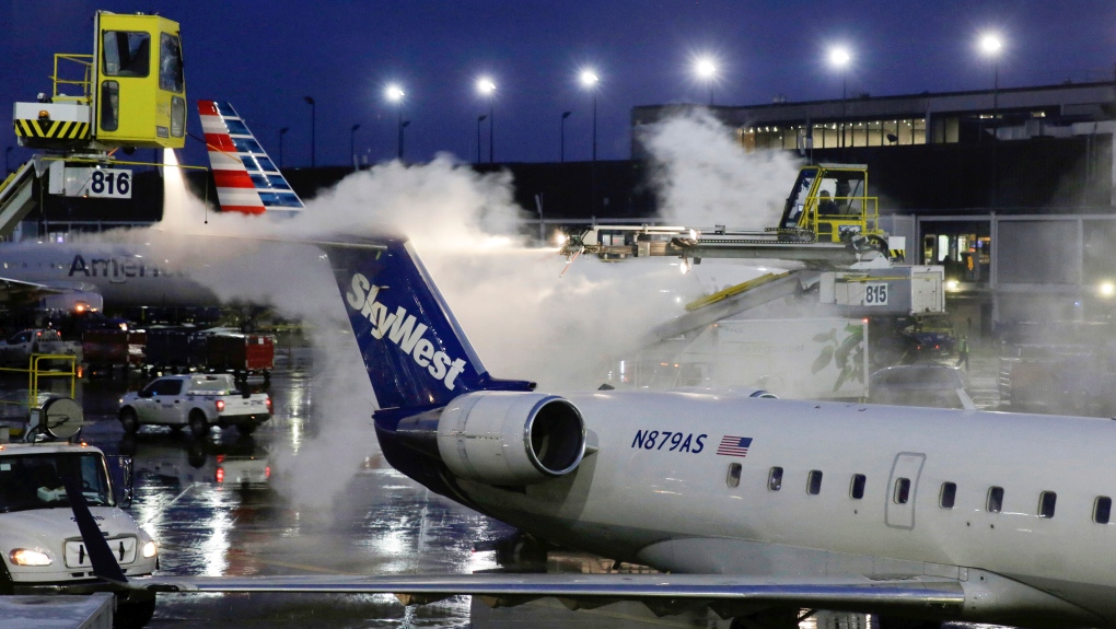 A deicing agent is applied to a SkyWest airplane before its takeoff on Jan. 18, 2019, at O'Hare International Airport in Chicago. The federal government filed a lawsuit against the airline, Wednesday, Aug. 17, 2022, on behalf of a former employee who says co-workers sexually harassed her, including asking her for sex and making explicit comments about rape in her presence. (AP Photo/Kiichiro Sato, File)