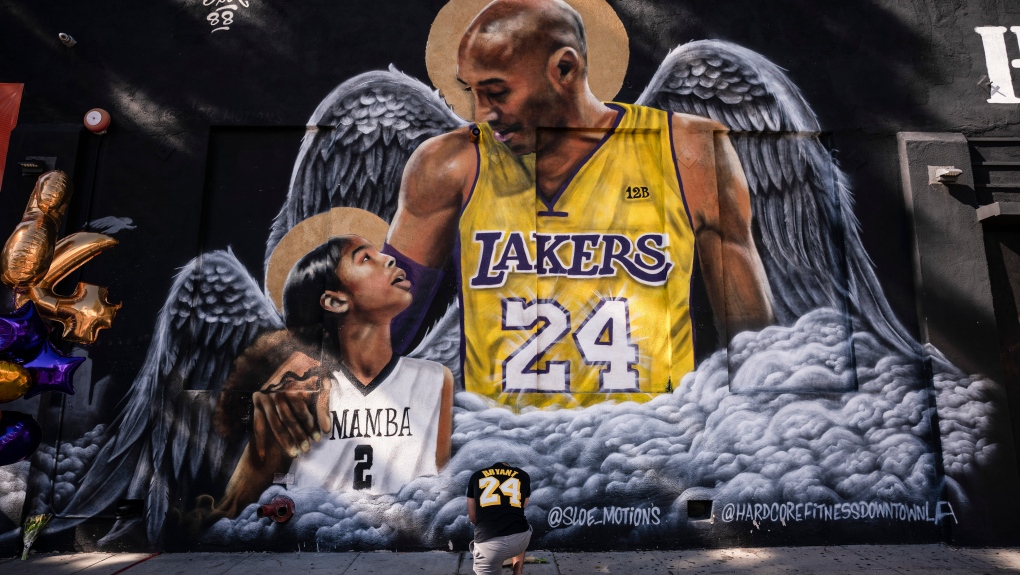 In this Jan. 26, 2021, file photo, Adam Dergazarian, bottom centre, pays his respects for Kobe Bryant and his daughter, Gianna, in front of a mural painted by artist Louie Sloe Palsino in Los Angeles. (AP Photo/Jae C. Hong, File)
