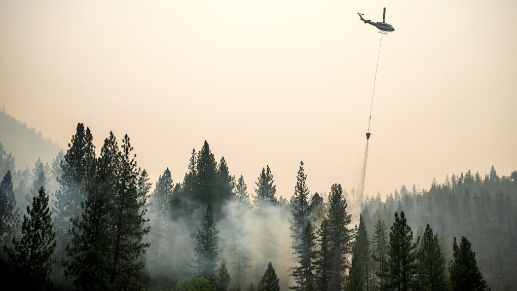 A helicopter drops water on a hot spot while battling the McKinney Fire, Aug. 2, 2022, in Klamath National Forest, Calif. (AP Photo/Noah Berger)