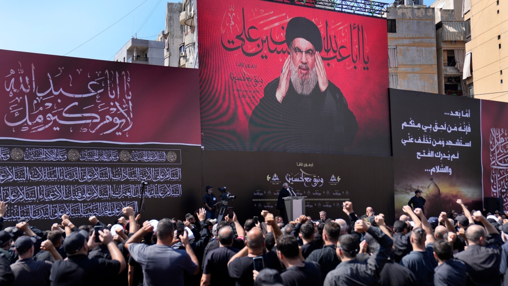 Hezbollah leader Sheik Hassan Nasrallah, greats his supporters as he speaks via a video link, during the holy day of Ashoura that commemorates the 7th century martyrdom of the Prophet Muhammad's grandson Hussein, in the southern suburb of Beirut, Lebanon, in Beirut, Lebanon, Tuesday, Aug. 9, 2022. (AP Photo/Hussein Malla)