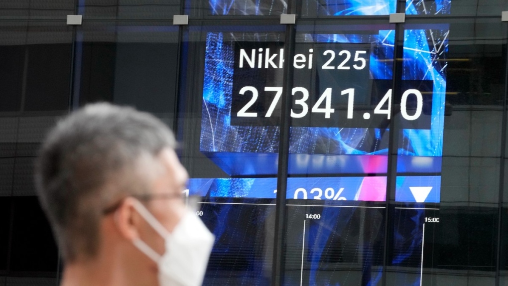 A person wearing a protective mask stands in front of an electronic stock board showing Japan's Nikkei 225 index at a securities firm, Sept. 7, 2022, in Tokyo. (AP Photo/Eugene Hoshiko)