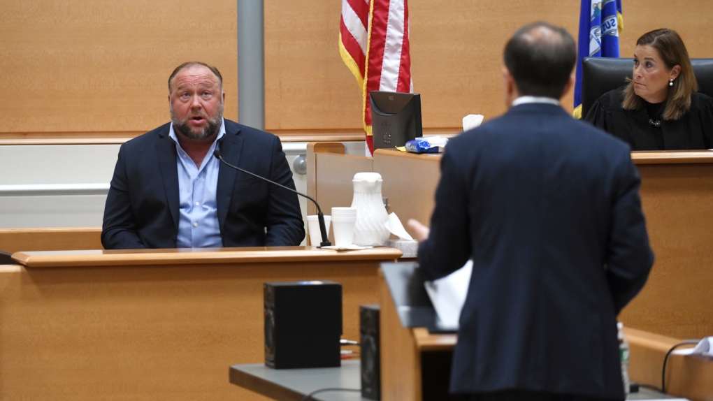 Infowars founder Alex Jones, left, is questioned by plaintiff's attorney Chris Mattei beside Judge Barbara Bellis, right, during testimony at the Sandy Hook defamation damages trial at Connecticut Superior Court in Waterbury, Conn. Thursday, Sept. 22, 2022. (Tyler Sizemore/Hearst Connecticut Media via AP, Pool)