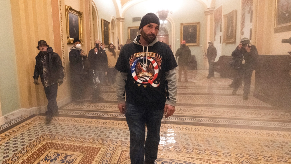 Smoke fills the walkway outside the Senate Chamber as supporters of Donald Trump, including Douglas Jensen, centre, are confronted by U.S. Capitol Police officers, Jan. 6, 2021, inside the Capitol in Washington. (AP / Manuel Balce Ceneta)